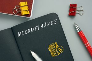 Microfinance’ written on black page in notebook to represent the concept of microfinance