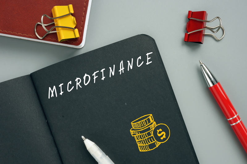 microfinance written on black paper in notebook to represent the concept of microfinance