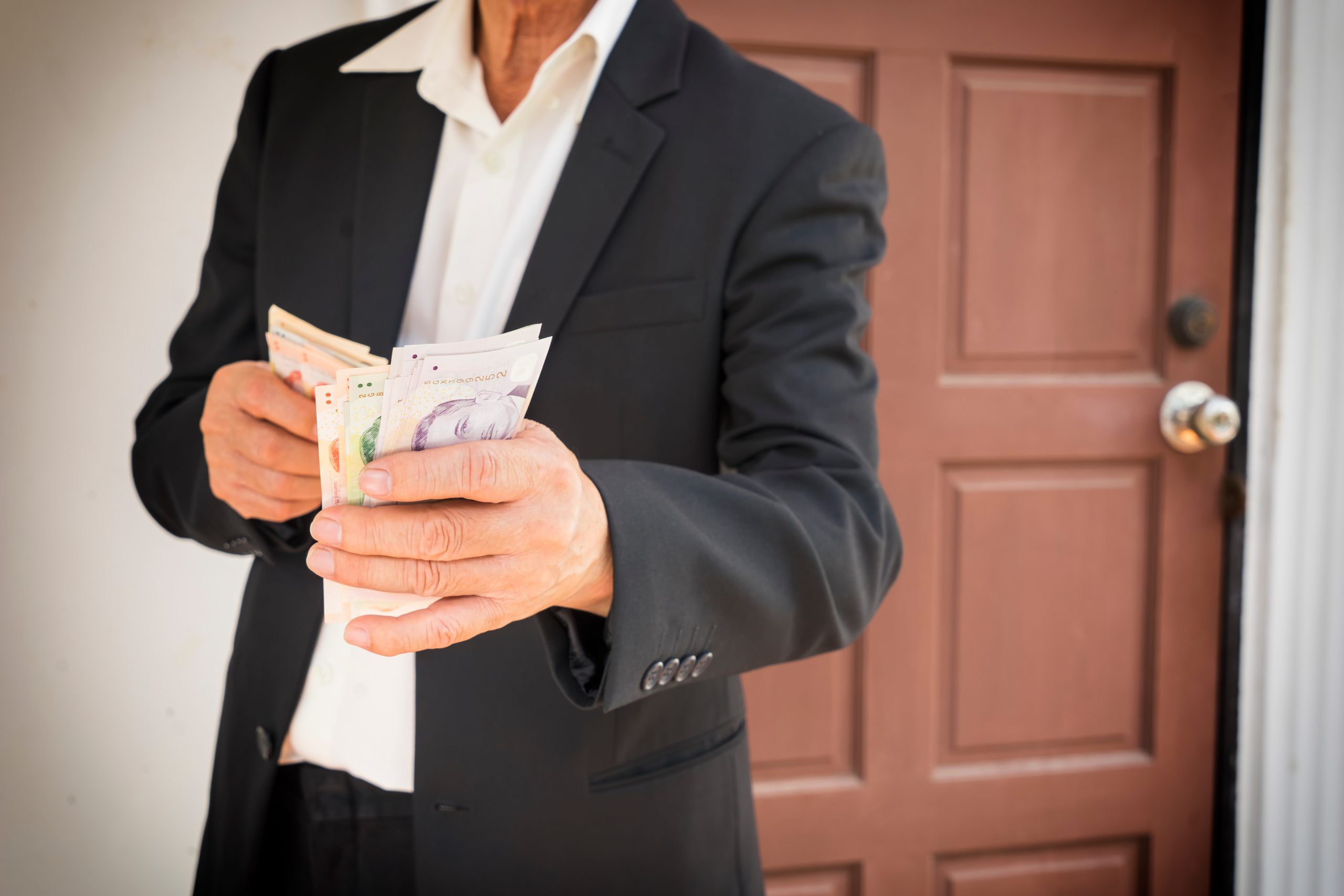 A businessman in a suit holding a stack of cash after getting his personal loan approved