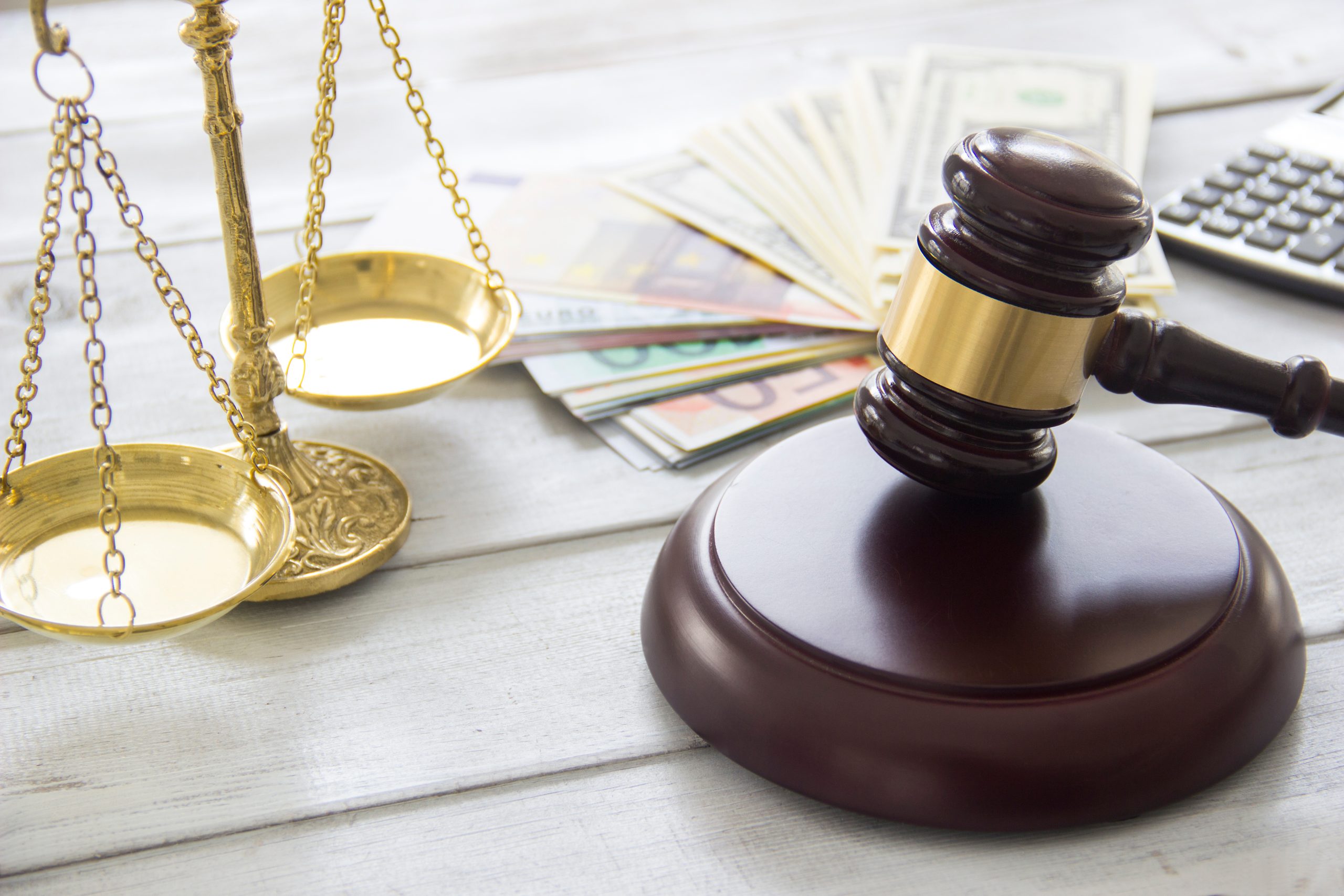 A close-up of a weighing scale, gavel, money and calculator, representing the legitimacy of a money lender