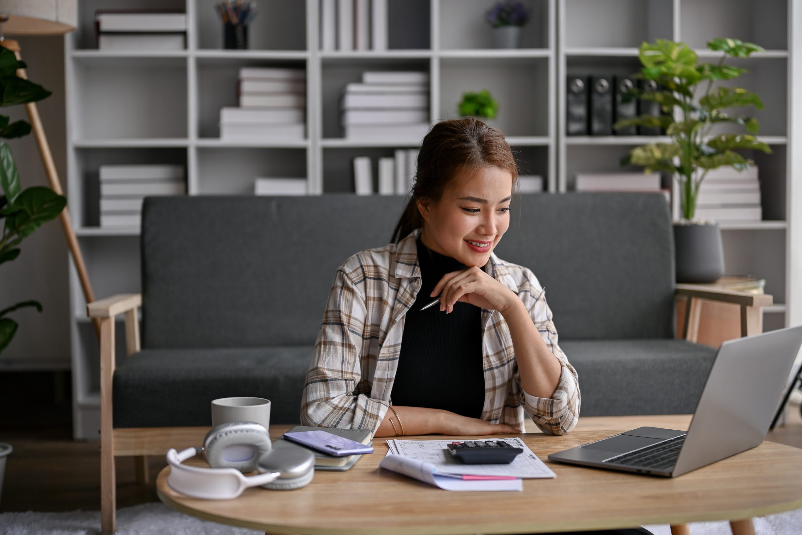 An asian lady in checkered outerwear smiling after receiving a loan offer with a flexible repayment plan