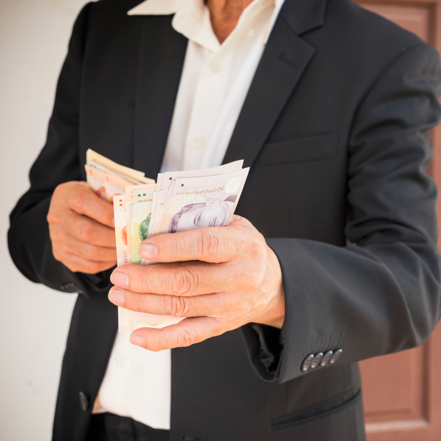 A businessman in a suit holding a stack of cash after getting his personal loan approved